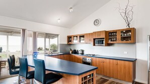 A modern kitchen with wooden cabinets, a blue countertop, and a built-in microwave. - Hindmarsh Hideaway-—Waterfront Pet-friendly Living (Hindmarsh Island)