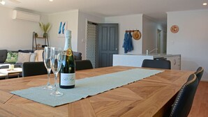 A dining area with a wooden table, two wine glasses, and a bottle of champagne.