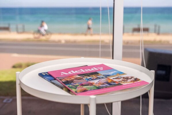 A magazine on a small table with a view of a beach and people in the background.