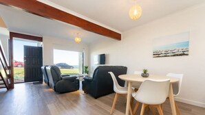 Un salon moderne comprenant un canapé, des fauteuils, une table à manger et un téléviseur.