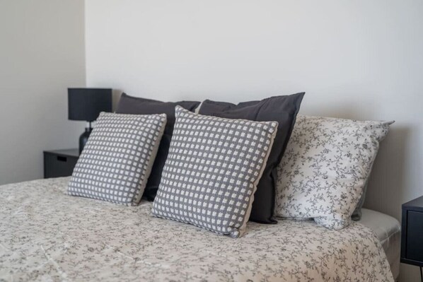 A bed with a floral bedspread, two patterned pillows, and a plain pillow. - South Seas 5 - Absolute Beachfront Escape near Cafés (Port Elliot)
