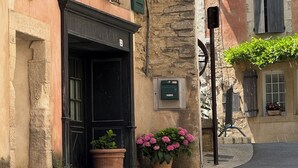 A narrow street with historic buildings, stone walls, and a black door. - La Gloriette en Luberon 15 minutes from GORDES (Goult)