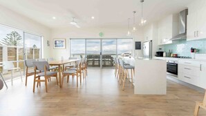 Una cocina moderna con armarios blancos, una isla central y un comedor con sillas de madera.