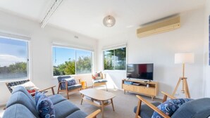 Un salon moderne avec un ensemble de canapés, une table basse et un téléviseur posé sur un meuble en bois.