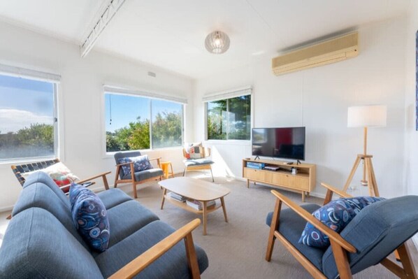 A modern living room with a sofa set, a coffee table, and a TV on a wooden stand.