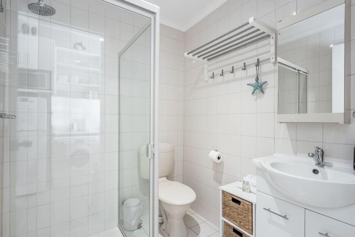 Een moderne badkamer met een douchecabine van glas, een toilet, een wastafel en een handdoekhouder.