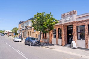 Une vue de rue avec une rangée de bâtiments, dont un bâtiment en briques sur lequel on peut lire l’inscription « solt ».