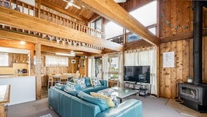 A cozy cabin interior with a wooden interior, a sofa, a dining area, and a TV.