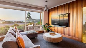 A modern living room with a large TV, a sofa, and a view of the outdoors.