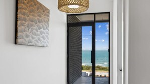 A modern interior with a large sliding glass door leading to a balcony with a view of the ocean. - Seamist on Seagull with Expansive Views (Hayborough)