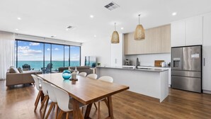 A modern kitchen with a large island, stainless steel appliances, and a view of the ocean. - Seamist on Seagull with Expansive Views (Hayborough)