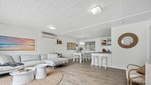 A spacious living area with a sofa, coffee table, and dining table. - Percy`s Place: Family-friendly Waterfront Serenity (Goolwa)