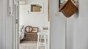 A hallway leading to a bedroom with a bed, a wicker basket, and a framed picture on the wall. - Percy`s Place: Family-friendly Waterfront Serenity (Goolwa)