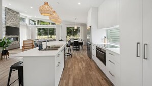 A modern kitchen with white cabinetry, a central island, and a dining area with a view.