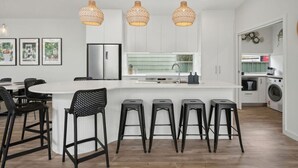 A modern kitchen with a central island, bar stools, and pendant lighting.