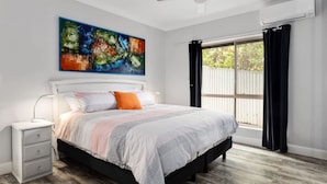 Un dormitorio con cama, mesita de noche y ventilador de techo.