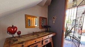 Una consola de madera con cajones y cestas, un globo rojo y dos espejos enmarcados en una pared.