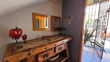 Une console en bois dotée de tiroirs et de paniers, un globe terrestre rouge et deux miroirs encadrés accrochés à un mur.