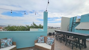A rooftop patio with wicker furniture, a dining table, and chairs. - Pool, Park & Ocean - Centro Home (Mazatlan)