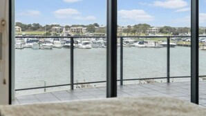 Vista desde un balcón sobre un puerto deportivo con barcos y edificios al fondo.