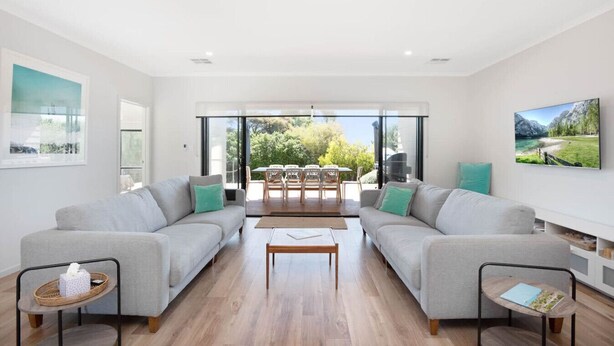 A modern living room with two sofas, a coffee table, and a dining area with chairs and a table.