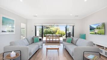 A modern living room with two sofas, a coffee table, and a dining area with chairs and a table.