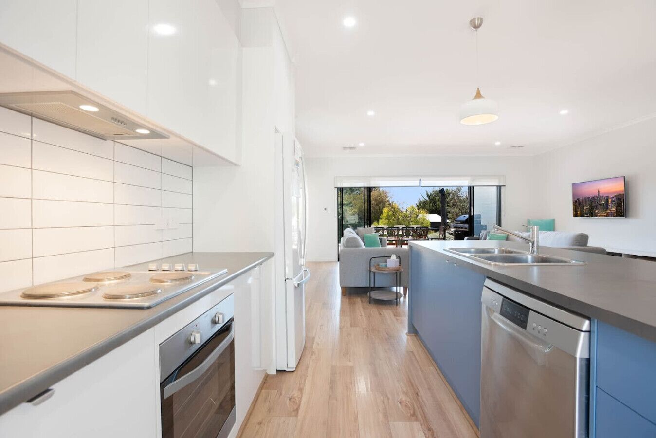 A modern kitchen with a central island, built-in oven, and a large window overlooking a patio area.
