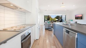 A modern kitchen with a central island, built-in oven, and a large window overlooking a patio area.