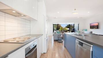 A modern kitchen with a central island, built-in oven, and a large window overlooking a patio area.