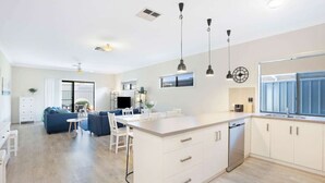 A modern kitchen with white cabinets, a central island, pendant lights, and a large window. - Brooking’s Perch - Riverside Stay near Cafés & Wharf (Goolwa)