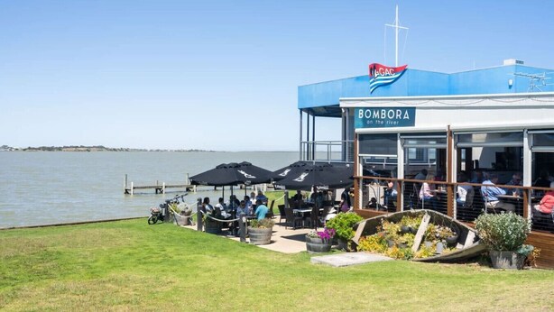 A waterfront restaurant named 'BOMBORA on the river' with outdoor seating and umbrellas. - Brooking’s Perch - Riverside Stay near Cafés & Wharf (Goolwa)