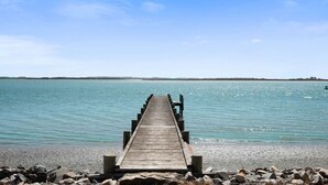 Een houten steiger die zich uitstrekt over kalm water, met een heldere lucht erboven.