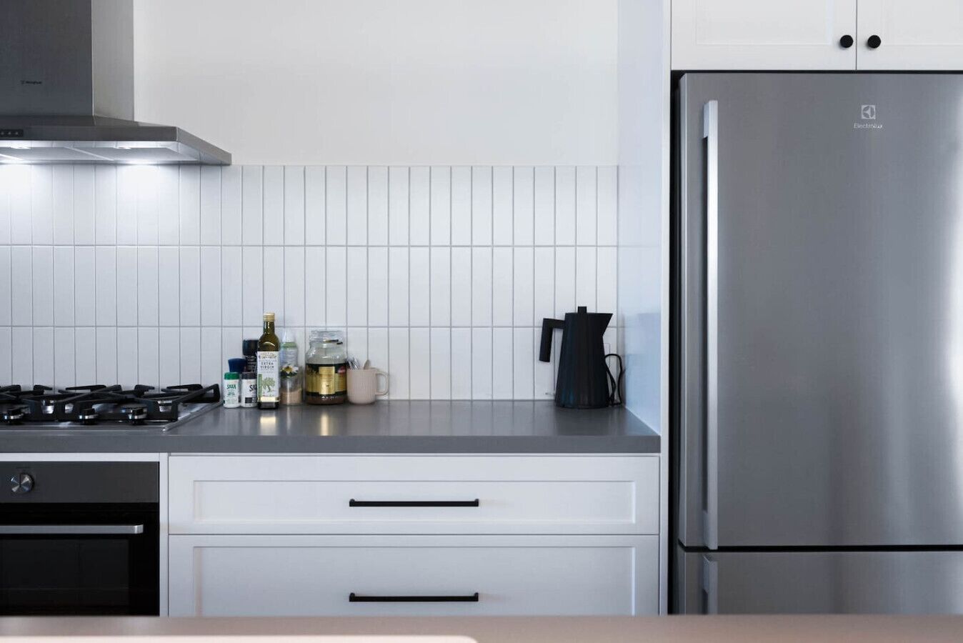 Une cuisine moderne équipée d’un réfrigérateur en acier inoxydable, d’une cuisinière à gaz et de meubles blancs.