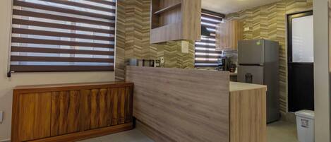 A modern kitchen with wooden cabinetry, a built-in island, and a refrigerator.