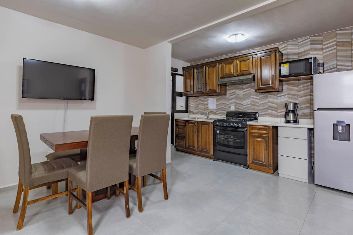 A compact kitchen with wooden cabinets, a built-in microwave, a stove, and a refrigerator.