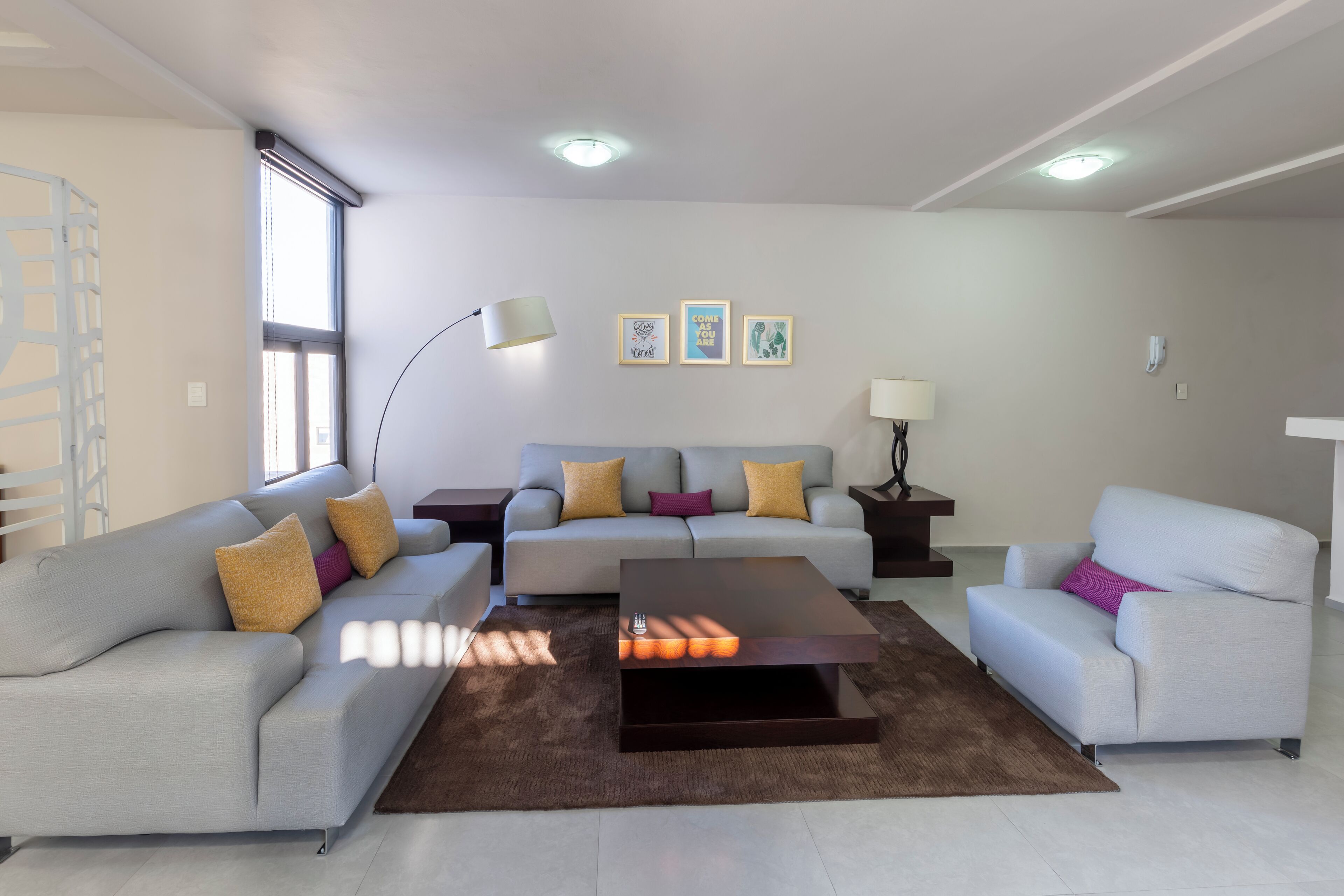 Ein modernes Wohnzimmer mit einer Sofagarnitur, einem Couchtisch und einer Stehlampe.