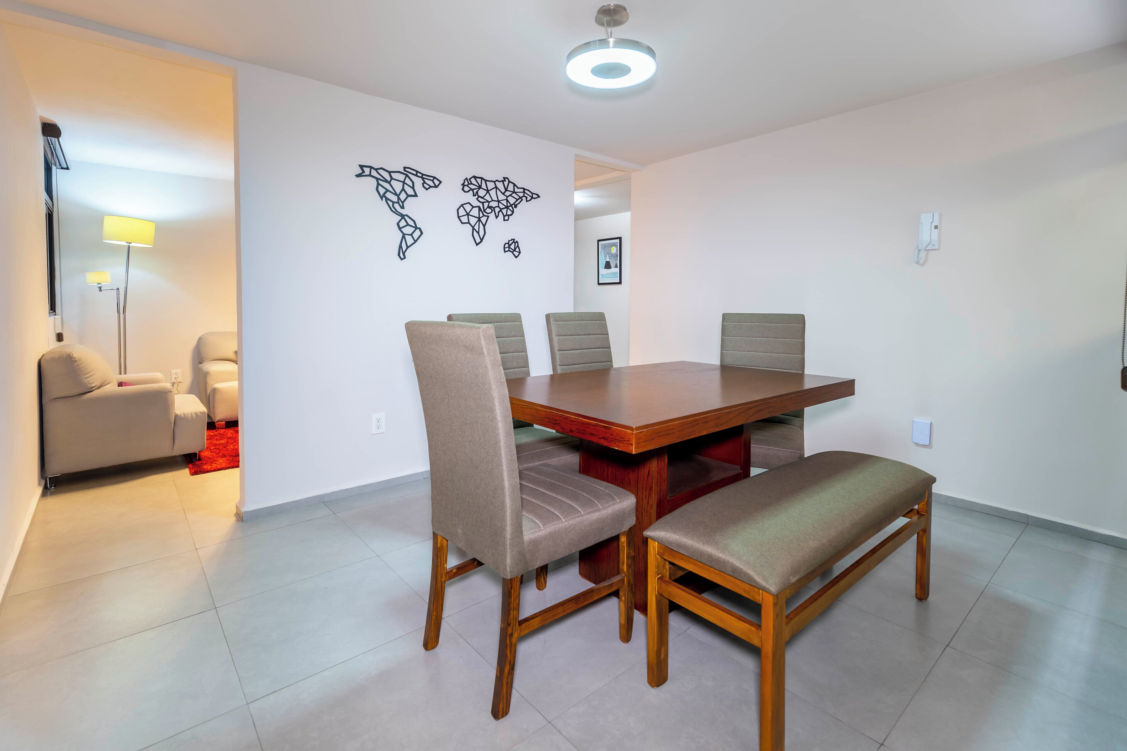Een eethoek met een houten tafel, zes stoelen, een bank en een rode vloerkleed op de achtergrond.