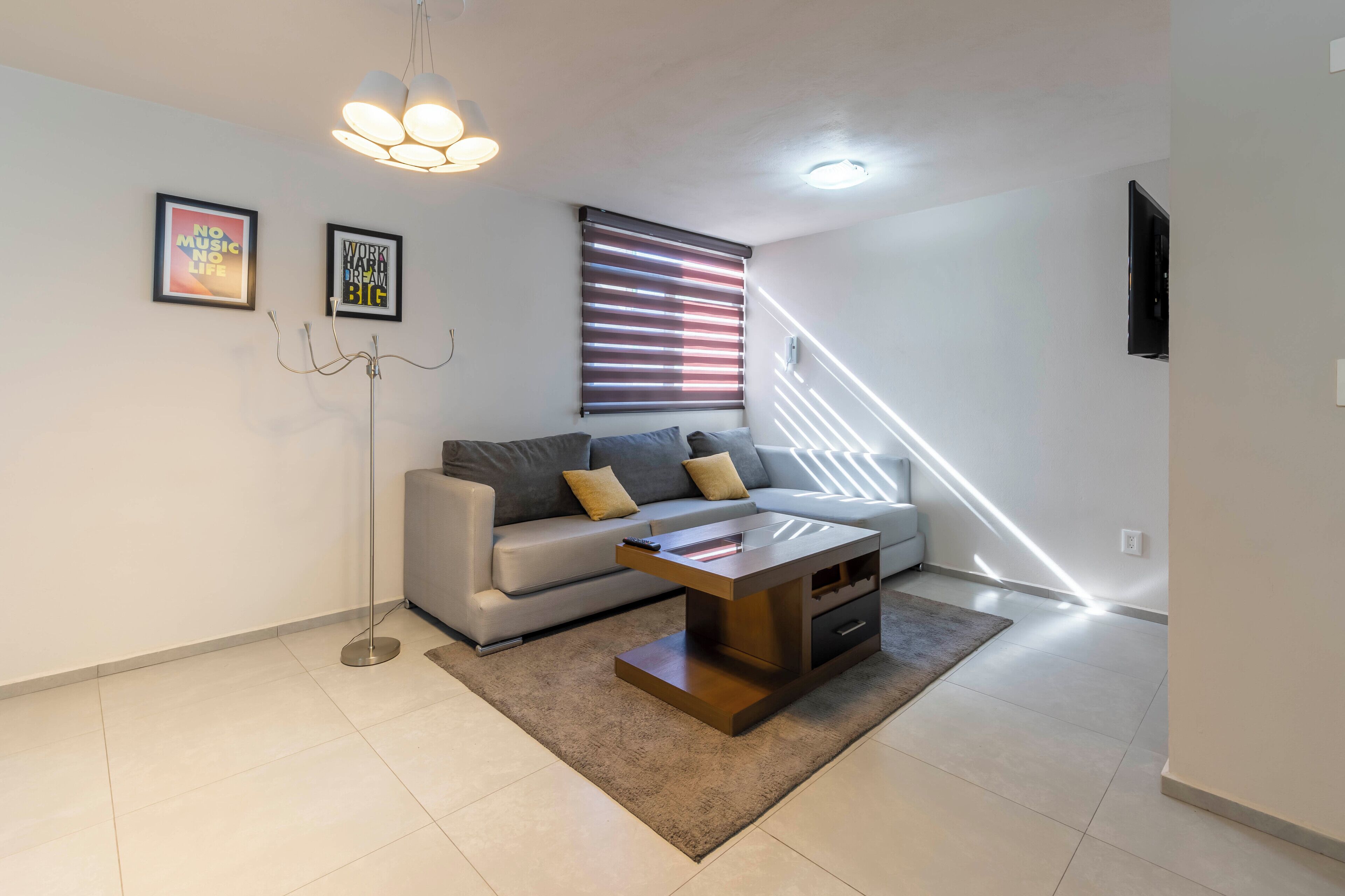 Una sala de estar moderna con un sofá gris, una mesa de centro de madera y una lámpara de pie.
