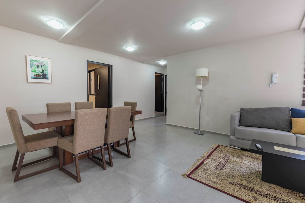 A modern living room with a dining area, a sofa, a floor lamp, and a rug.