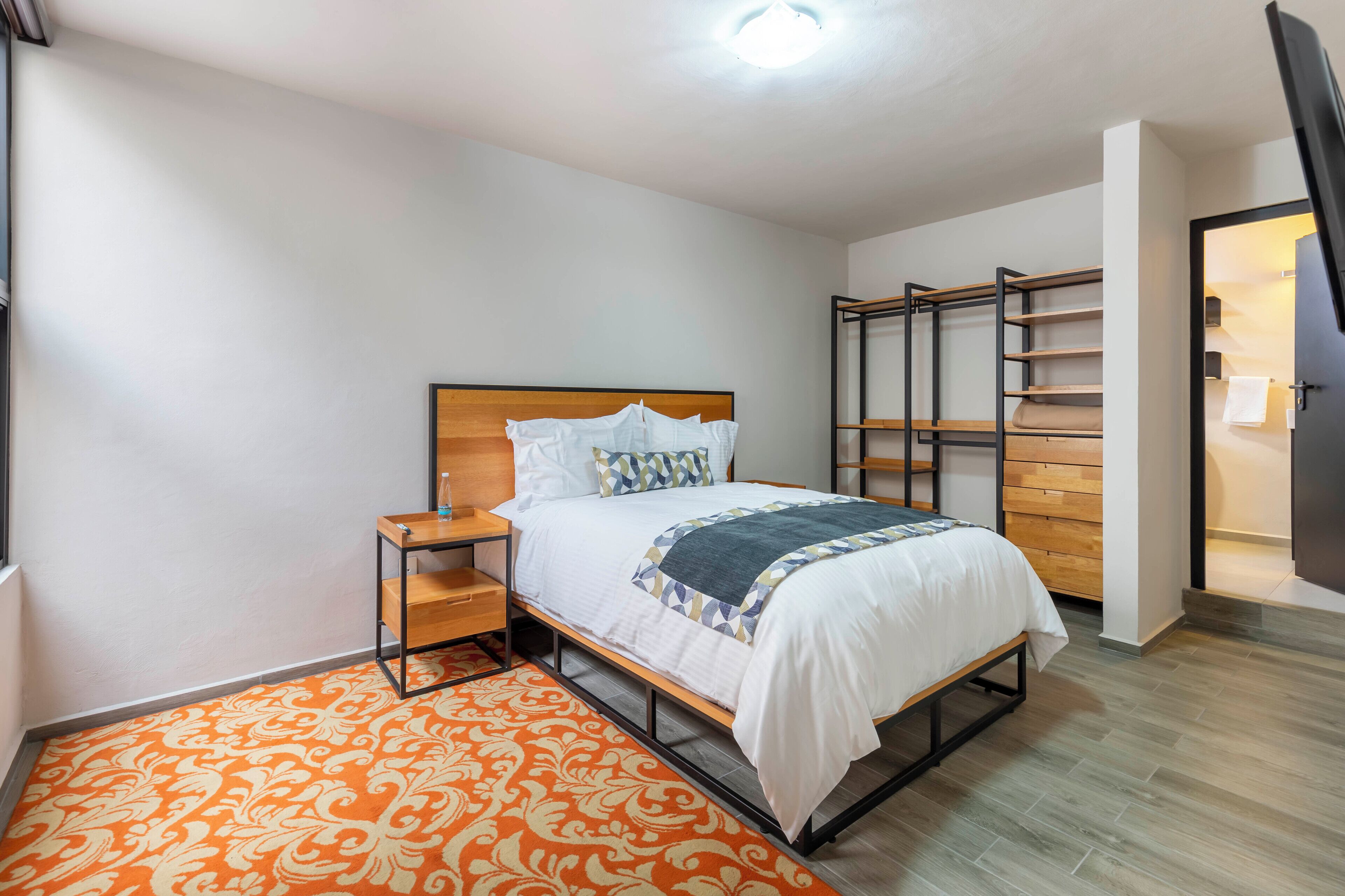A bedroom with a bed, nightstand, and built-in shelving unit.