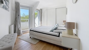 Une chambre à coucher avec un lit, une table de chevet, une lampe et une vue sur l’extérieur.