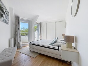 A bedroom with a bed, bedside table, lamp, and a view of the outdoors. - Vacation home for up to 8 people 10 min walk from the port La Trinité sur Mer (La Trinité-sur-Mer)