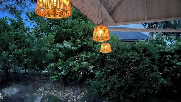 Un espace extérieur aménagé avec des meubles en bois et des lampes suspendues.