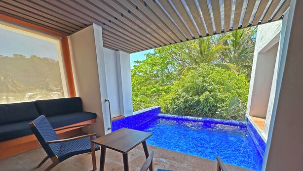 A modern outdoor seating area with a pool, a sofa, and a table. - Luxury beachfront condo with private pool & fast internet (Bahías de Huatulco)