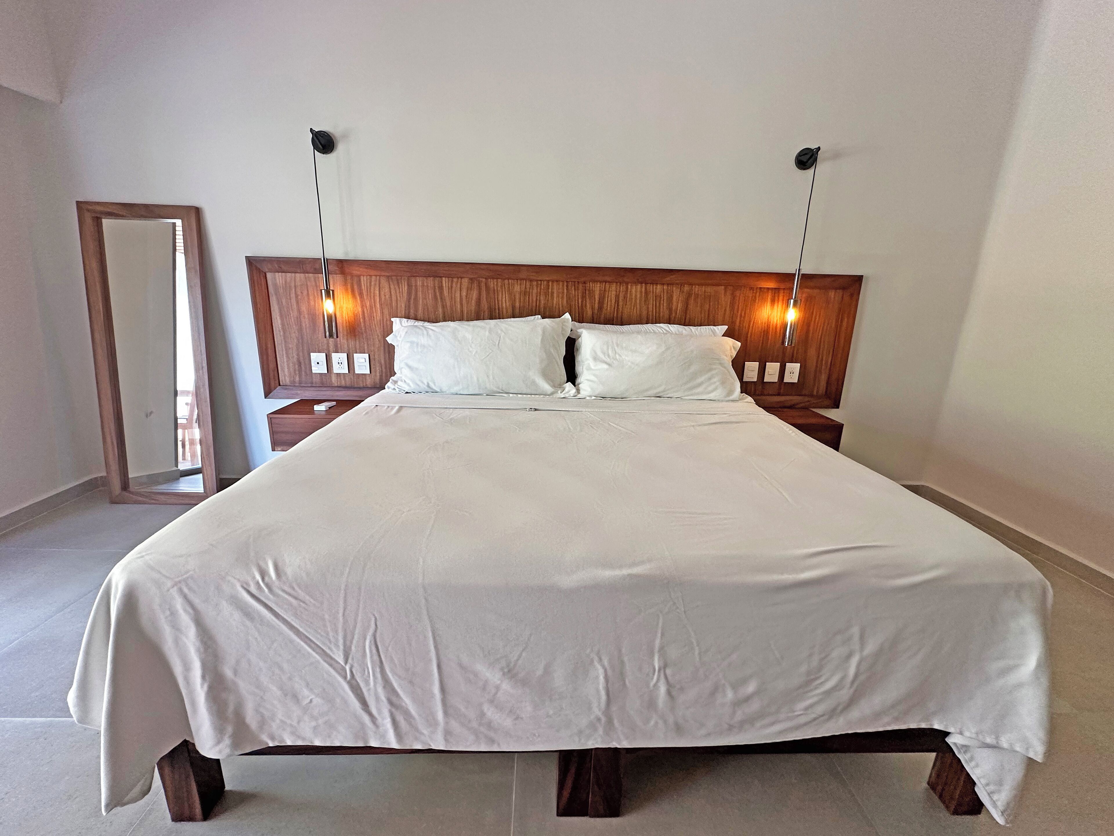 A large bed with a wooden headboard, white bedding, and two bedside lamps.