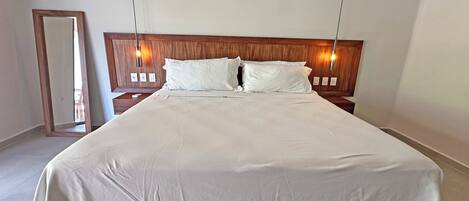A large bed with a wooden headboard, white bedding, and two bedside lamps.