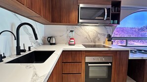 A modern kitchen with a built-in microwave, a kettle, a blender, and an oven. - Luxury beachfront condo with private pool & fast internet (Bahías de Huatulco)