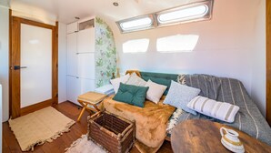 A cozy RV interior with a sofa, cushions, a small table, and a wicker basket.