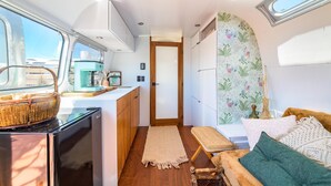 A compact kitchen with a coffee machine, a refrigerator, and a window overlooking a cityscape.