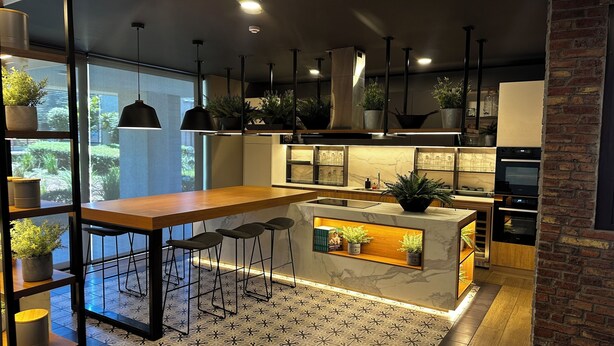 Een moderne keuken met een houten bar, zwarte hanglampen en potplanten.